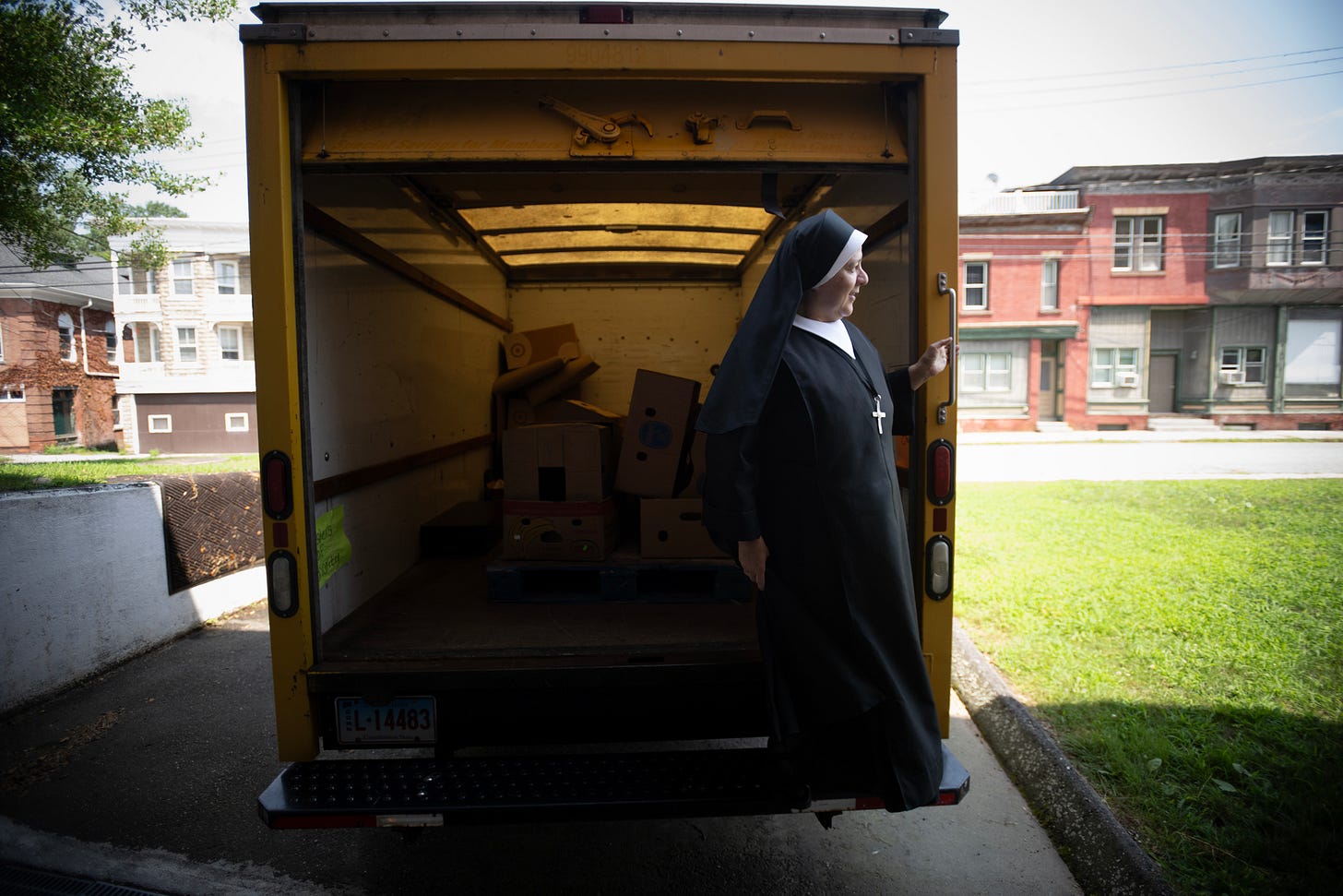 A Sister stands beside the community food pantry truck