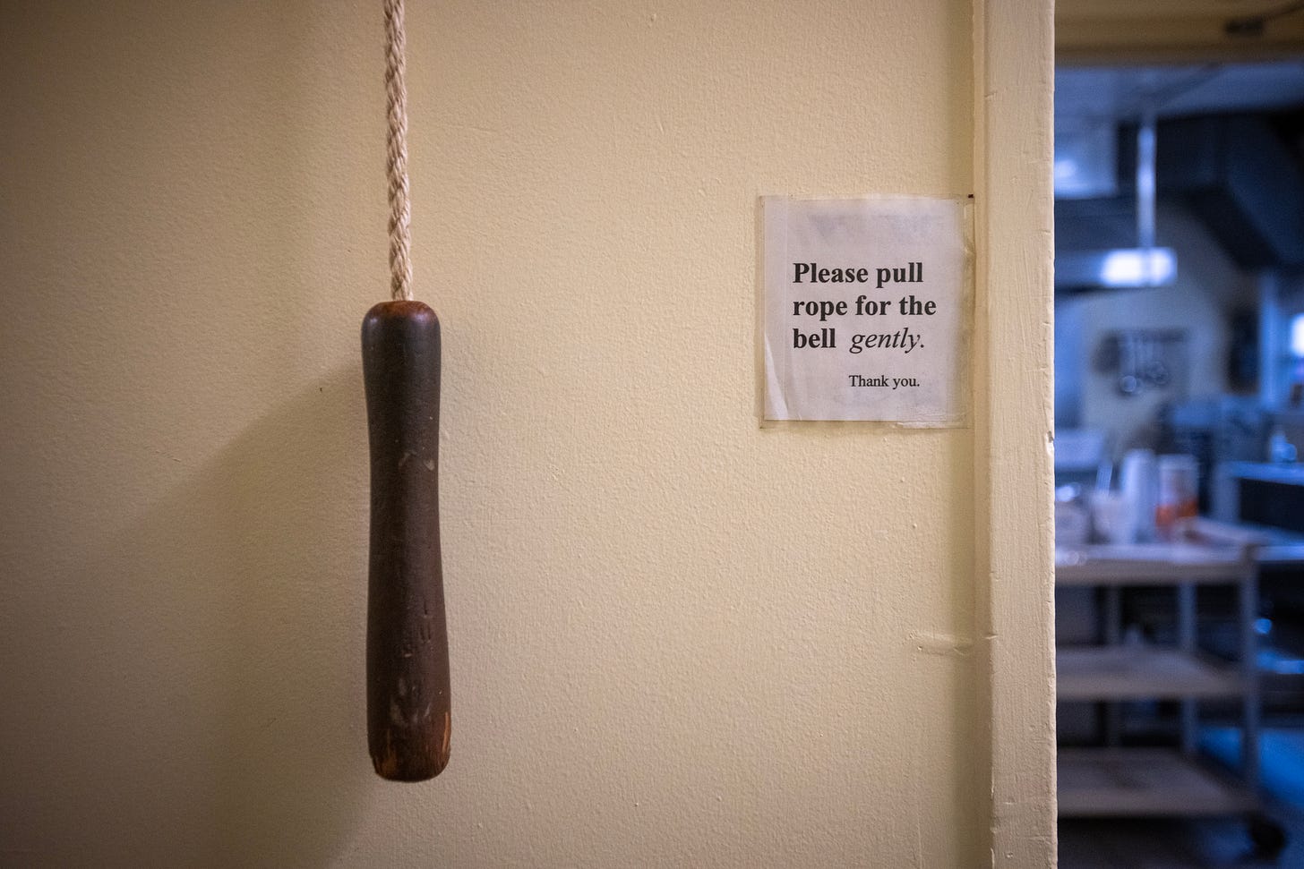 A pull cord beneath a sign asking visitors to pray for the bell ringer