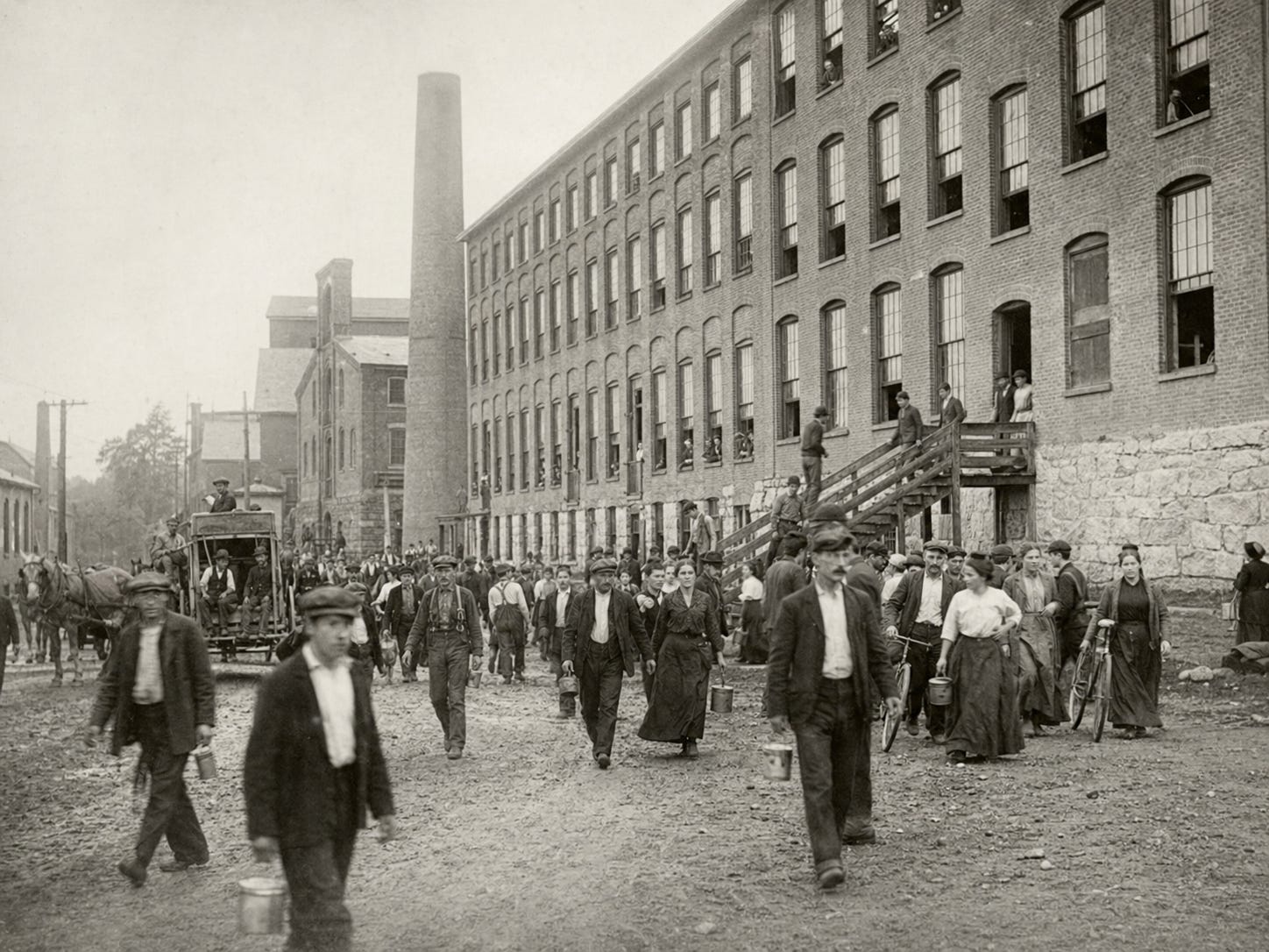 Mill workers stream past the brick factory buildings
