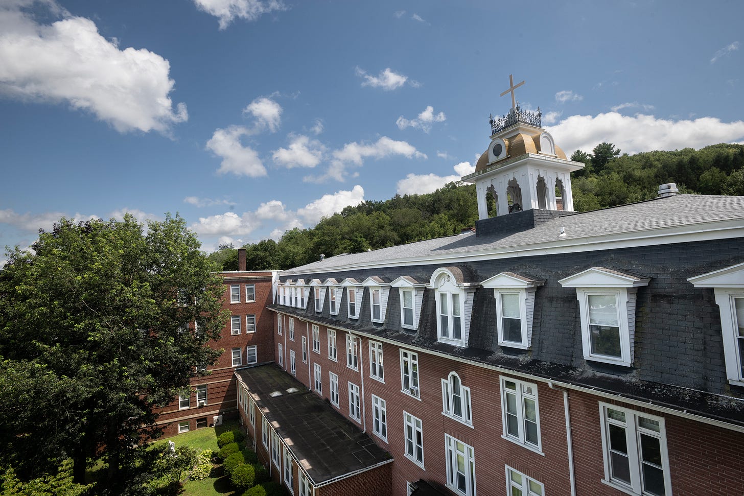 The Holy Family Motherhouse rises above the trees beneath a blue sky