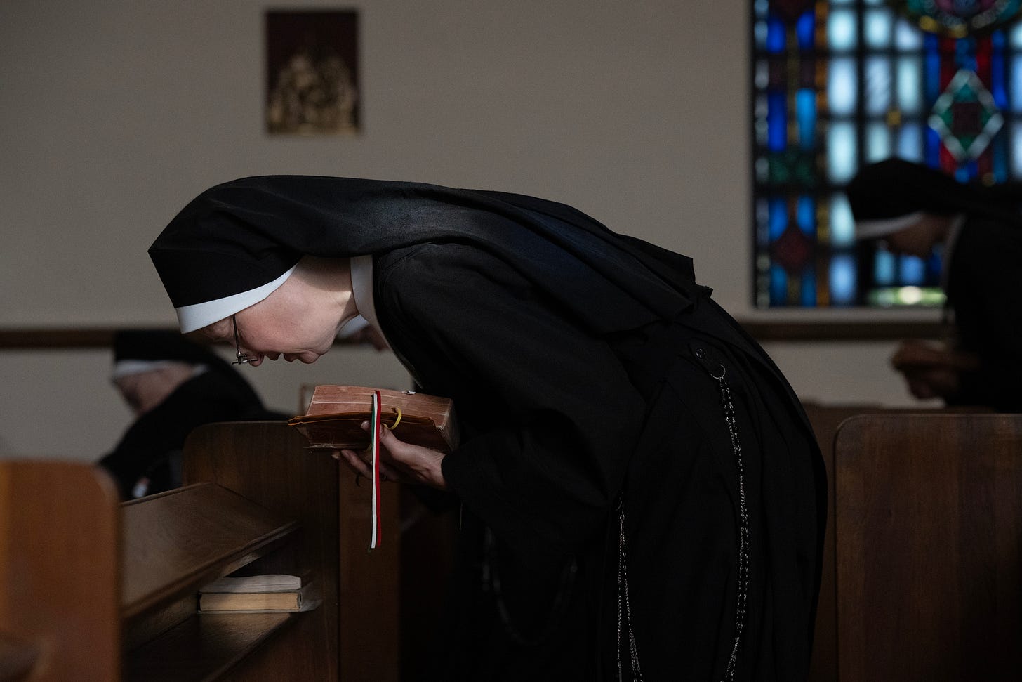 A Sister bows over her prayer book during the Divine Office