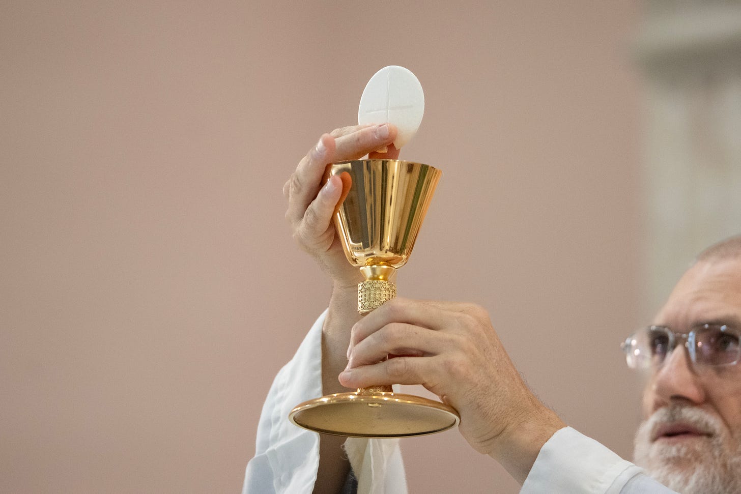A priest elevates the Eucharist during Mass