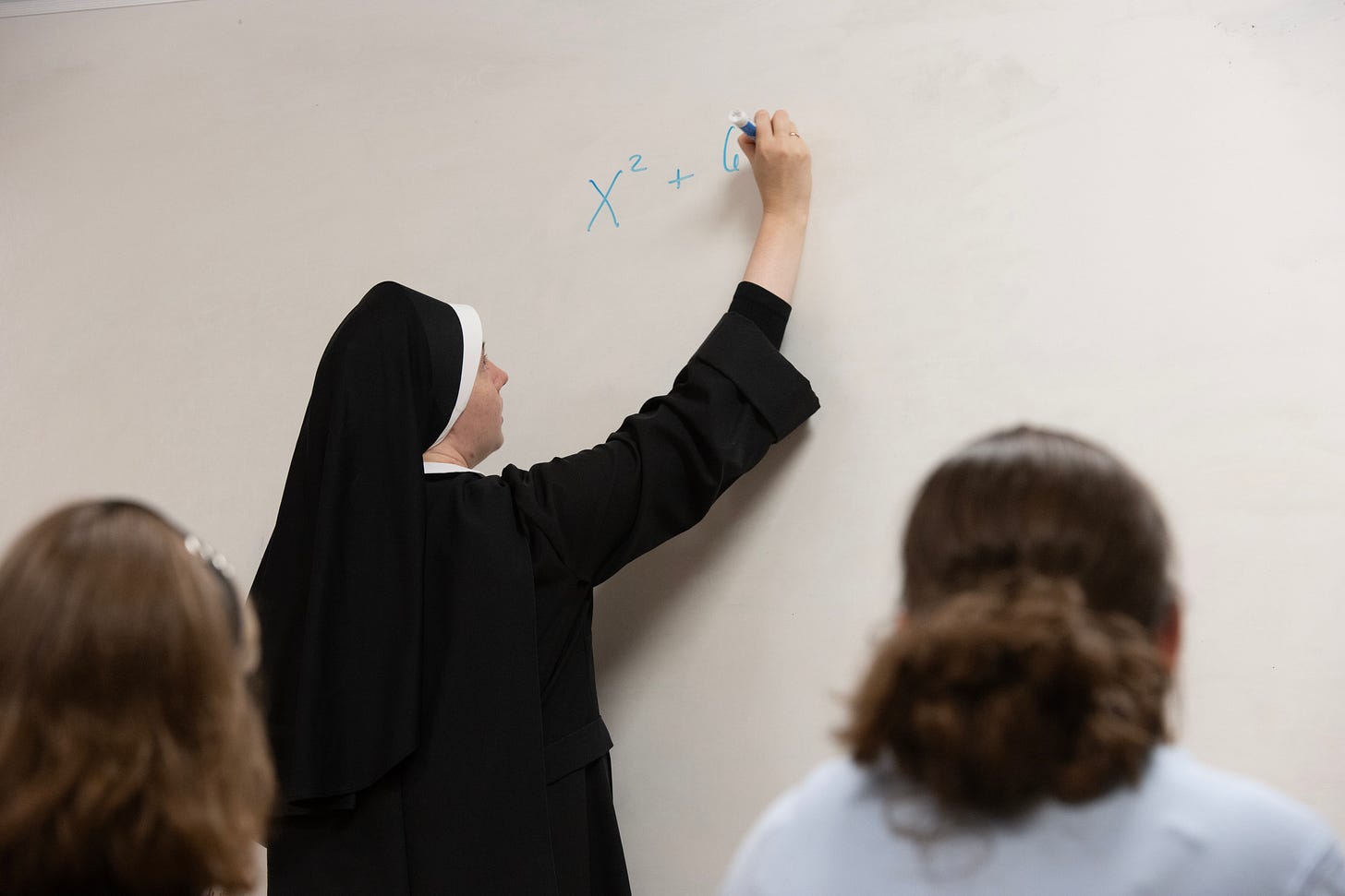 A Sister teaches students at the Academy of the Holy Family