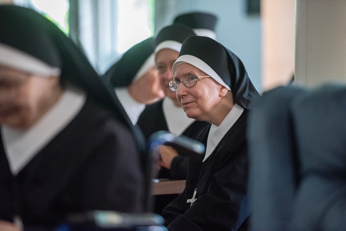 Sisters share conversation around a refectory table