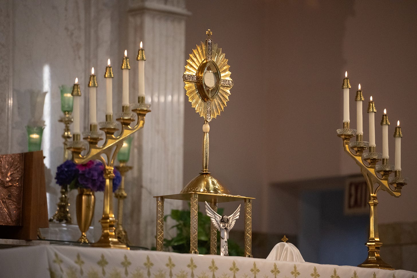 A monstrance and candles stand ready before the altar