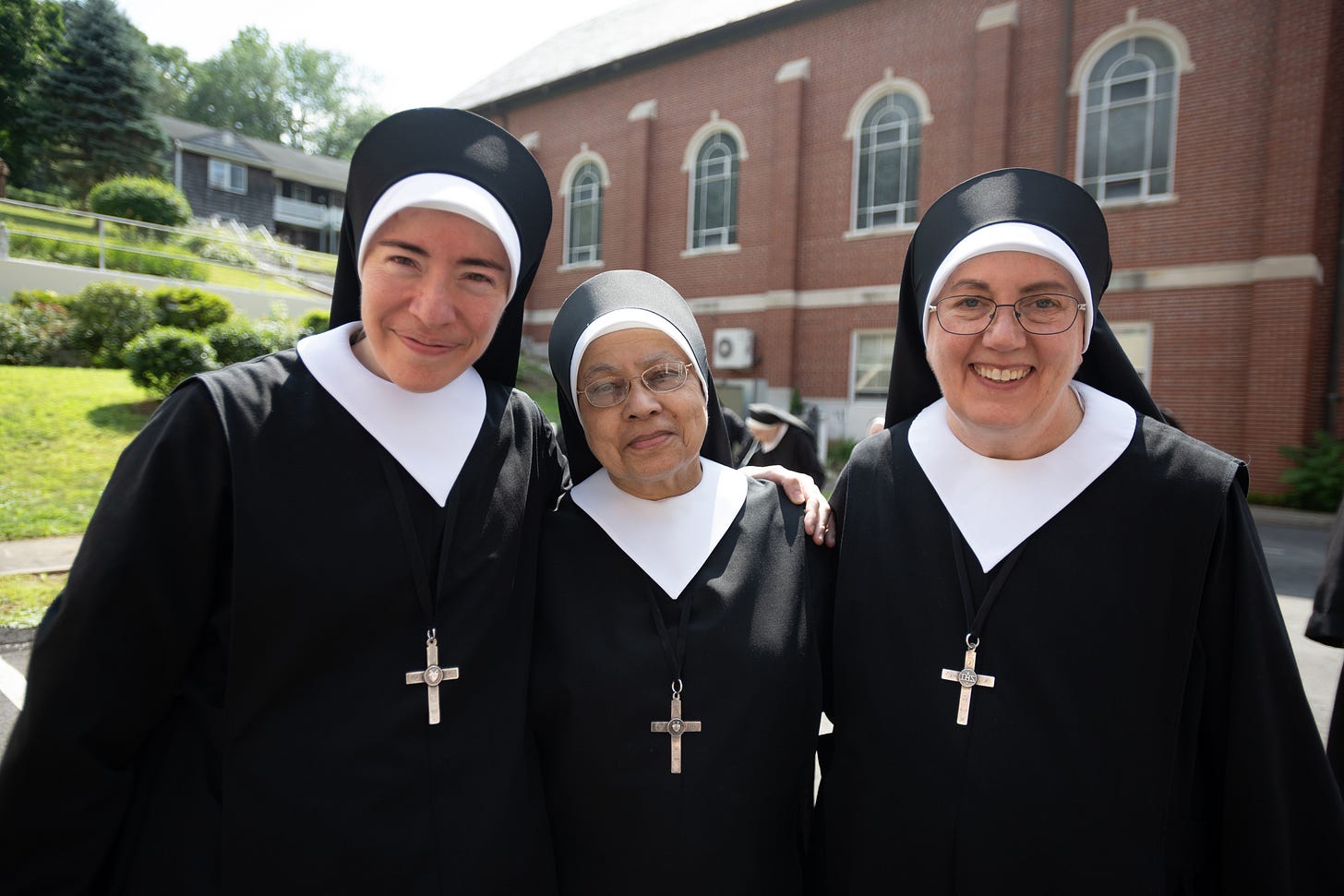 Three Sisters smile together outside the Motherhouse