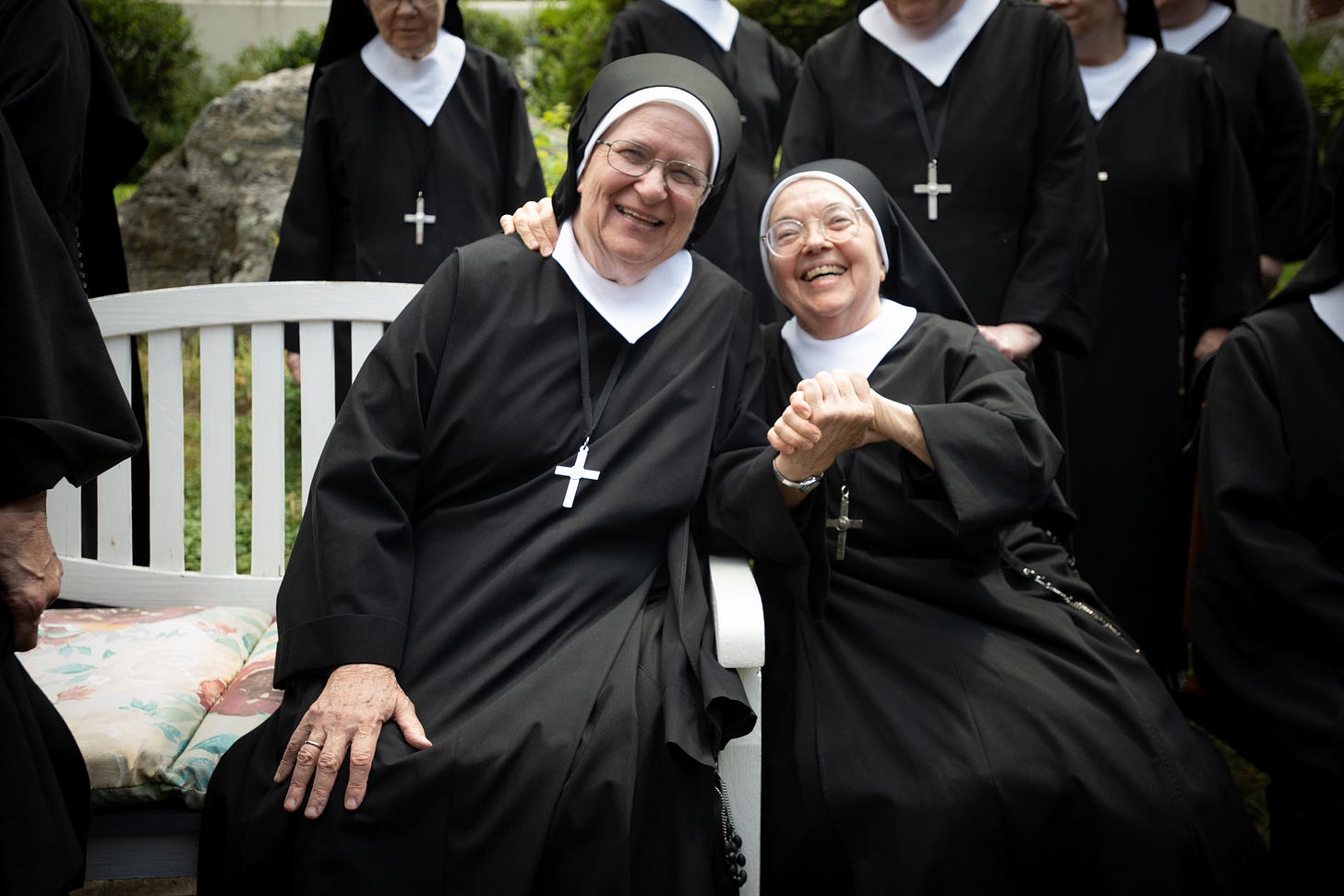 Two Sisters laugh together while seated outdoors
